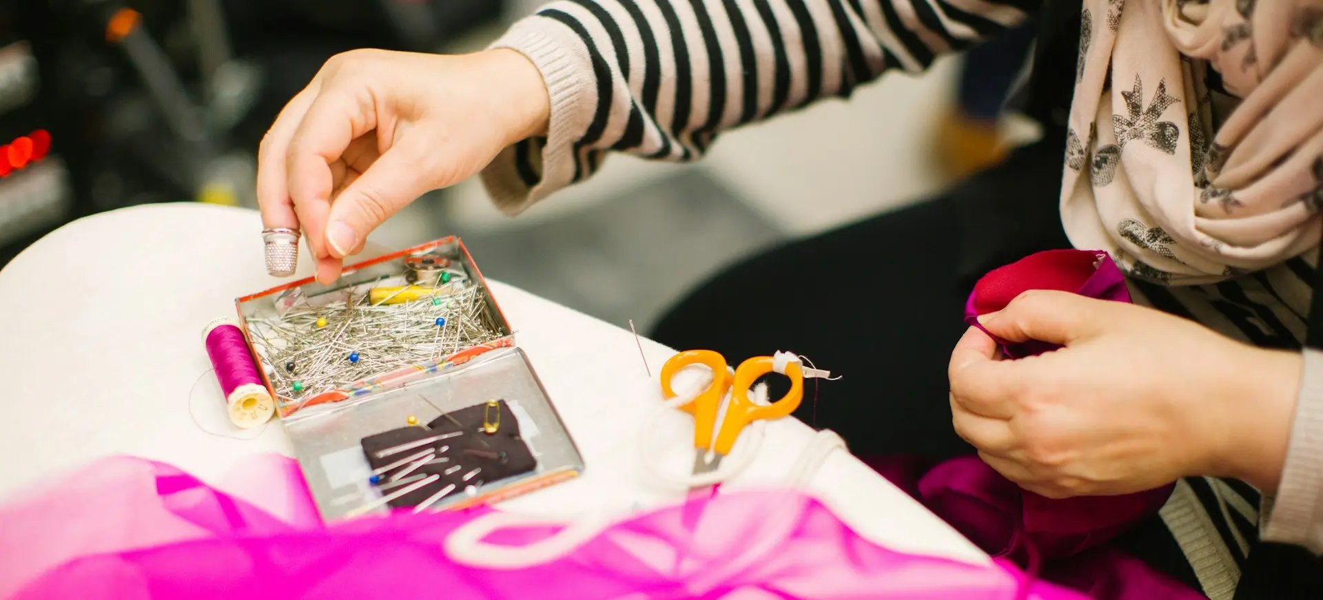 person holding pin using right hand and red mesh cloth using left hand